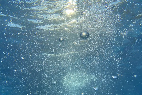 Air bubbles rising through clear blue water