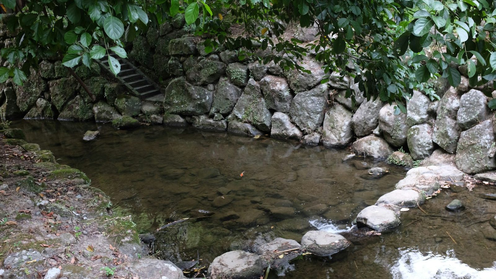 Shallow stream flowing through a stone-lined garden channel