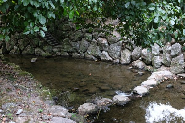 Shallow stream flowing through a stone-lined garden channel