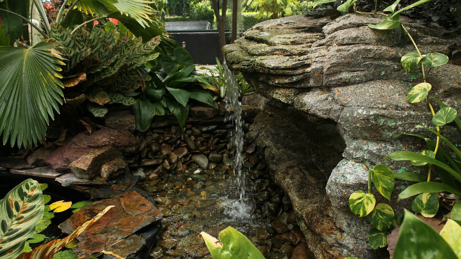 Thin trickle of water running over a rock waterfall in a garden