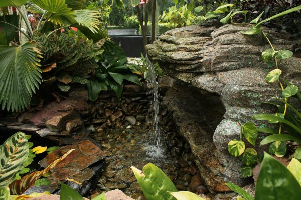 Thin trickle of water running over a rock waterfall in a garden